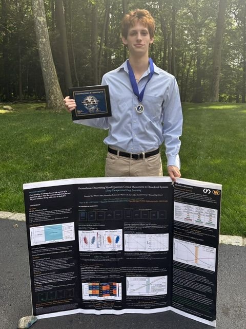 Wilson holding an award next to his research poster