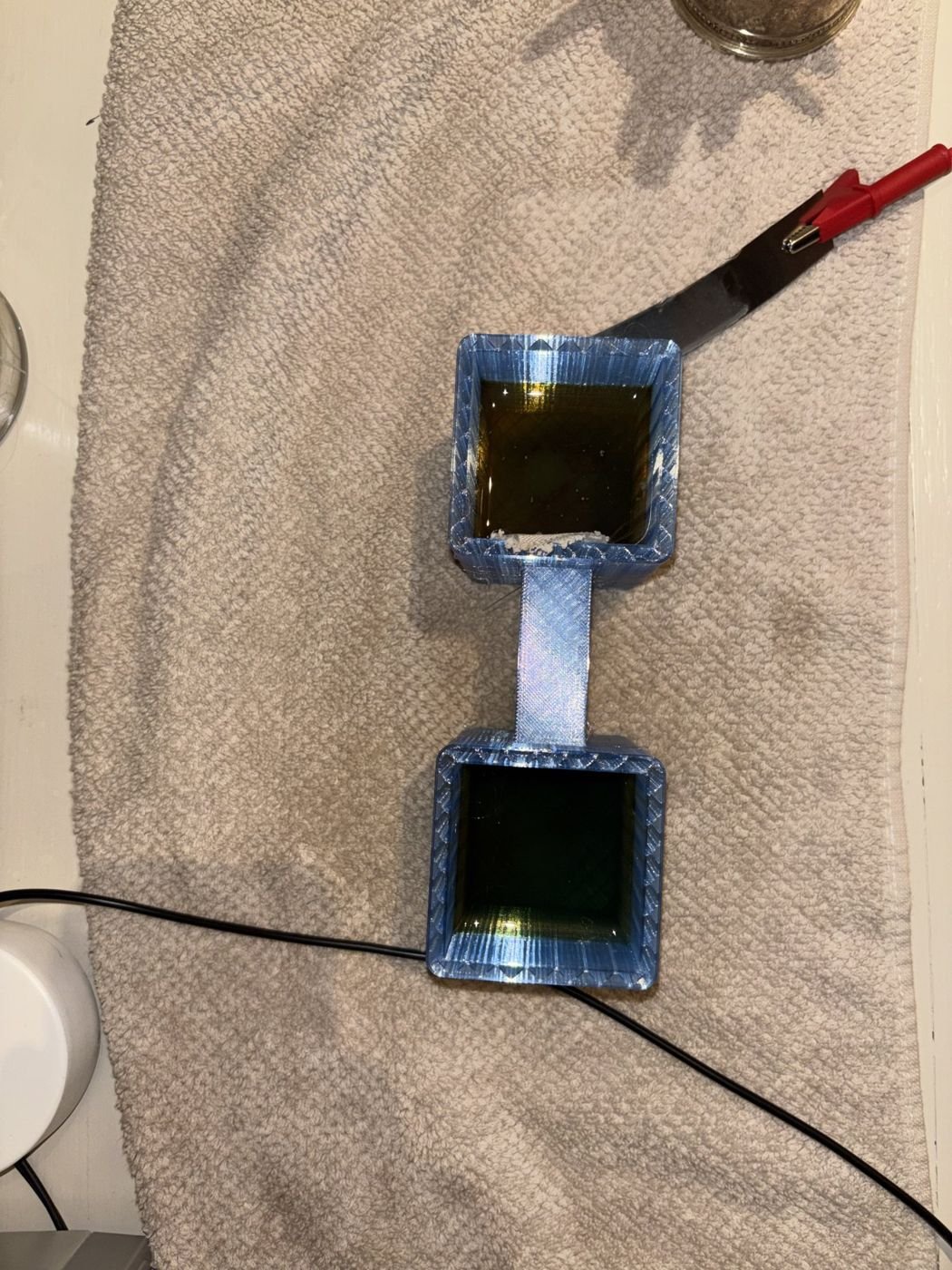 Top view of the same cell 90 minutes later with the electrodes unplugged; the two chambers hold differently colored solutions